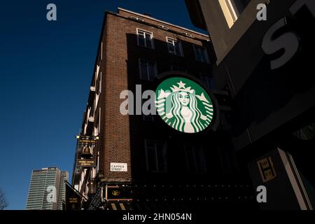 Das Starbucks Logo fängt an einem kalten Wintertag in London, Großbritannien, das Sonnenlicht auf der Tottenham Court Road auf Stockfoto