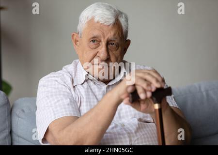 Einsamer, müde, depressiver älterer Mann, der auf dem Sofa zu Hause sitzt Stockfoto