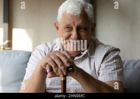 Glücklicher älterer 80s Mann mit Behinderung, der einen Stock hielt Stockfoto