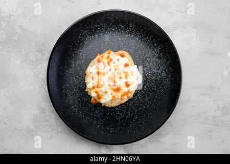 Gehacktes Schweinekotelett, das mit Schinken und Käse auf einem Teller gebacken wurde Stockfoto