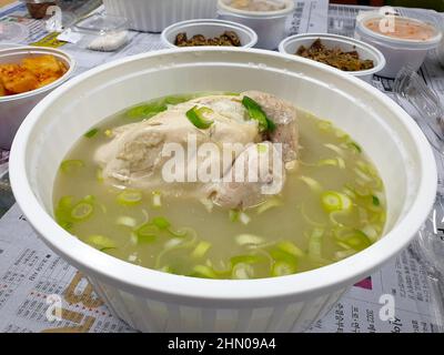 Ulsan, Südkorea - Samgyetang wird in einer Kunststoffschale geliefert. Traditionelle koreanische Suppe mit Huhn, gefüllt mit Knoblauch, Reis, Jujube und Ginseng. Stockfoto