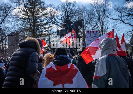 Toronto, Kanada. 12th. Februar 2022. Demonstranten mit kanadischen Flaggen umzingelten ein Denkmal während einer Kundgebung.Trucker Konvoi Demonstranten versammeln sich am zweiten Wochenende in Folge im Queen's Park, Toronto, um sich solidarisch mit Anti-Mandats-Demonstrationen zu zeigen. Er kommt, nachdem die Provinz den Ausnahmezustand in Bezug auf die anhaltenden Blockaden erklärt hat, und die Polizei von Toronto Straßensperrungen in der ganzen Stadt eingerichtet hat. (Foto von Katherine Cheng/SOPA Images/Sipa USA) Quelle: SIPA USA/Alamy Live News Stockfoto