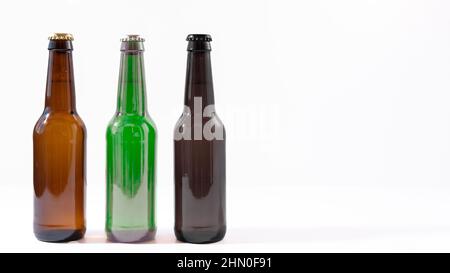 Verschiedene farbige Bierflaschen und Deckel auf weißem Hintergrund Stockfoto
