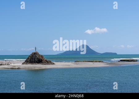 Whale Island vor der Küste von Whakatane mit Lady on Rock-Statue in den Hafenköpfen. Stockfoto