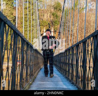 ABERLOUR,MORAY,SCHOTTLAND - 11. FEBRUAR 2022: Dies ist ein Piper, der über die Penny Bridge läuft, um die Lachsfischerei am Fluss Spey at zu beginnen Stockfoto