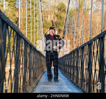 ABERLOUR,MORAY,SCHOTTLAND - 11. FEBRUAR 2022: Dies ist ein Piper, der über die Penny Bridge läuft, um die Lachsfischerei am Fluss Spey at zu beginnen Stockfoto