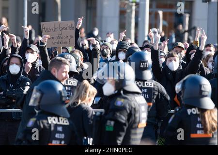 Dresden, Deutschland. 13th. Februar 2022. Gegendemonstranten reagieren hinter Polizisten während einer Kundgebung von Neonazis auf dem Postplatz. Die Prozession, die als schweigender marsch erklärt wurde, wurde von mehreren Gegendemonstrationen begleitet. Quelle: Sebastian Kahnert/dpa-Zentralbild/dpa/Alamy Live News Stockfoto