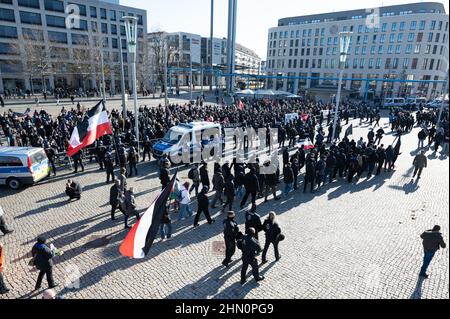 Dresden, Deutschland. 13th. Februar 2022. Zahlreiche Neonazis (vorne) gehen bei einer Kundgebung auf dem Postplatz vor Gegendemonstranten (hinten) entlang. Die Prozession, die als schweigender marsch erklärt wurde, wurde von mehreren Gegendemonstrationen begleitet. Quelle: Sebastian Kahnert/dpa-Zentralbild/dpa/Alamy Live News Stockfoto