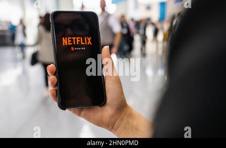 Netflix-App auf dem Apple iPhone. Junge Frau stöbert in der Film-Videothek, was sie sich ansehen kann. Stockfoto