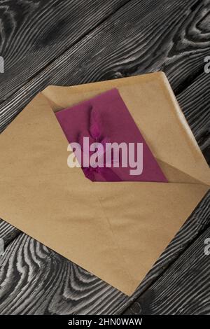 Grußkarte mit Statice-Zweigen und einem Umschlag. Auf Kiefernbrettern. Nahaufnahme. Stockfoto