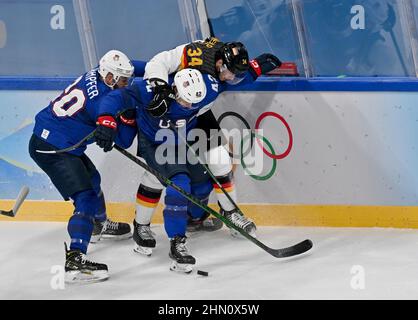 Peking, China. 13th. Februar 2022. Eishockey, Olympische Spiele, Vorrunde, Gruppe A, USA - Deutschland in der Wukesong Arena kämpft Tom Kühnhackl (hinten) aus Deutschland gegen Aaron Ness (M) und Steven Kampfer (l) aus den USA auf den Brettern. Kredit: Peter Kneffel/dpa/Alamy Live Nachrichten Stockfoto