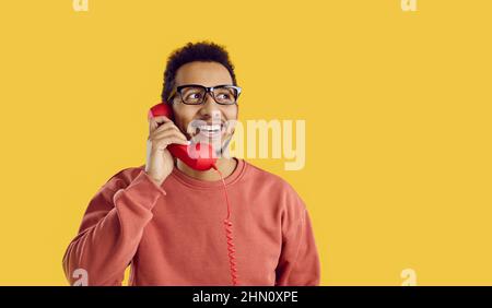 Glücklicher schwarzer Mann auf gelbem Hintergrund, der mit seinem Freund telefoniert und lächelt Stockfoto