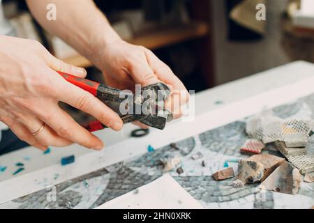 Handwerker Schneiden von Smaltglas mit Zangen Cutter für die Herstellung von Smaltglas Mosaik Stockfoto