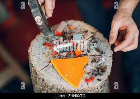 Handwerker schneidet zerbrechendes Smaltglas mit Hammer für Mosaikkunstwerke in der Werkstatt. Stockfoto