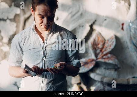 Handwerker männliche Meister Porträt halten Hammer und Smaltglas Stücke in Arm Hand für Mosaik-Kunstwerk in der Werkstatt. Stockfoto