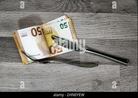 50-Euro-Banknoten mit Gabel und Messer auf einer Holzoberfläche Stockfoto