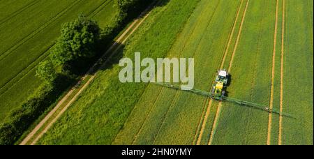 Luftaufnahme eines Traktors, der das Feld besprüht. Chemie in der Landwirtschaft aus Drohnensicht. Modernes landwirtschaftliches Hintergrundkonzept. Stockfoto