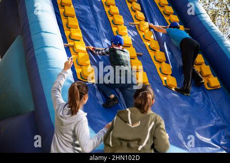 Freunde klettern auf aufblasbare Rutsche im Vergnügungspark Stockfoto