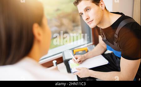 Der Handwerker schreibt auf die Zwischenablage mit der Frau, die in der Küche oder im Badezimmer steht Stockfoto