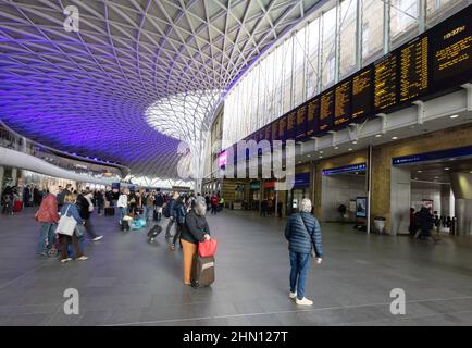 Bahnhof London Kings Cross, Bahnhofshalle; Passagiere, die auf die Abflugtafel schauen, Bahnhof Kings Cross, London, Großbritannien Stockfoto