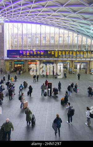 Bahnhof London Kings Cross, Bahnhofshalle; Passagiere, die auf die Abflugtafel schauen, Bahnhof Kings Cross, London, Großbritannien Stockfoto