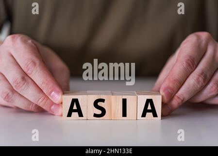 Ein Geschäftsmann hält Holzwürfel mit dem Wort Asien. Dieses seltene Wort eignet sich für jedes Ereignis und jeden Tag in Asien. Stockfoto