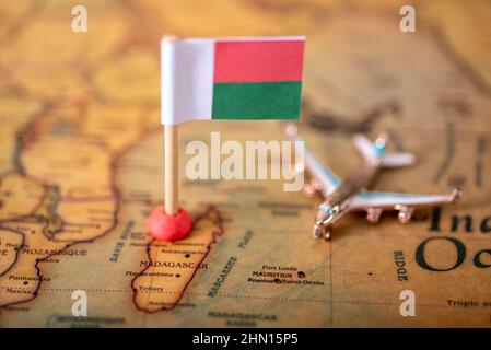 Die Flagge Madagaskars und das Flugzeug auf der Weltkarte. Das Konzept von Tourismus und Erholung. Stockfoto