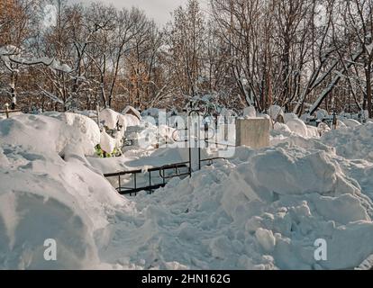 Ein schneebedeckter orthodoxer Friedhof. Eine Reihe von Gräbern mit Schnee bedeckt. Kreuze ragen aus dem Schnee. Stockfoto