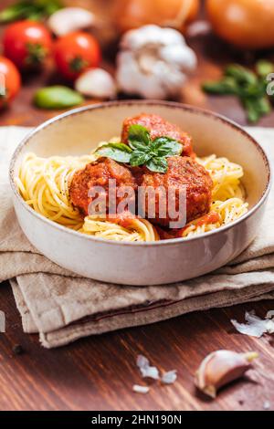 Rohes Hackfleisch, fertig für die Zubereitung von Fleischbällchen. Dekoriert mit Zutaten wie Zwiebeln, Basilikum, Tomatensauce, Pfeffer und Salz. Stockfoto