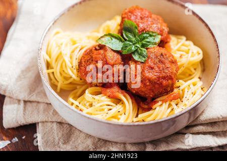 Rohes Hackfleisch, fertig für die Zubereitung von Fleischbällchen. Dekoriert mit Zutaten wie Zwiebeln, Basilikum, Tomatensauce, Pfeffer und Salz. Stockfoto
