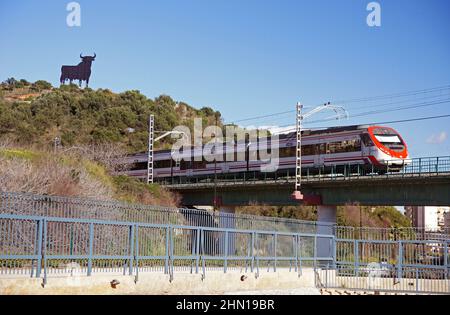 Andalusien in Spanien: Die Eisenbahnlinie in der Nähe der Stadt Fuengirola. Man beachte den Osborne-Stier (Toro d'Osborne) am Horizont Stockfoto