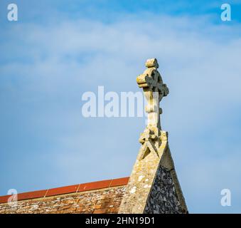 Enge und selektive Fokussierung auf ein religiöses Kreuz auf dem Dach einer kleinen ländlichen Kirche Stockfoto
