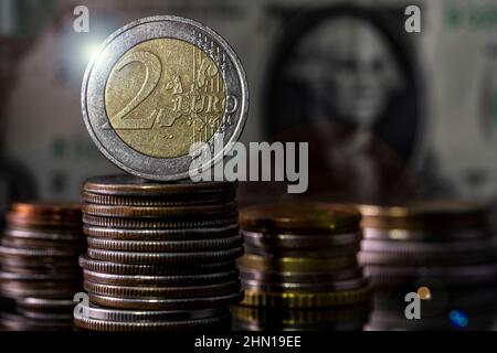 Wechselkursökonomik zwei Euro-Münzen auf dem obersten Haufen von Münzen Hintergrund der Dollarnoten verschwommen Stockfoto
