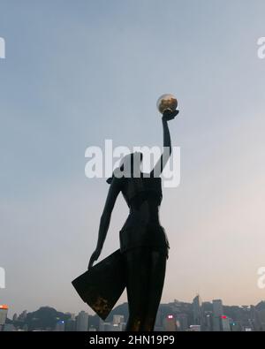 Hong Kong Film Awards Statue bei Sonnenuntergang mit Sonnenuntergang und Stadtbild von Hong Kong hinter Stockfoto