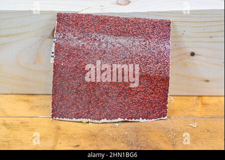 Ein bisschen rotes, raues Sandpapier auf einer Holzbank Stockfoto