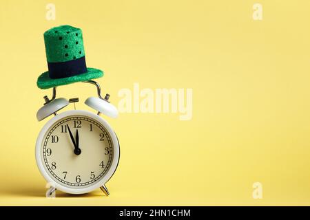 St. Patricks Day Feier Konzept. Wecker in einem grünen Hut auf gelbem Hintergrund. Stockfoto