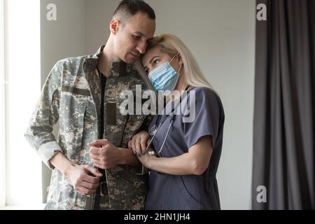 Fürsorgliche Krankenschwester, die die Hände hält und ihren militärischen Ehemann unterstützt, während sie im Krankenhaus mit ihm spricht Stockfoto