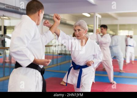 Porträt einer Frau im weißen Kimono-Sparring mit männlichem Gegner während des Kampfkunsttrainings Stockfoto