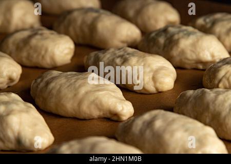 Der Teig wird auf ein Backblech im Ofen gelegt Stockfoto