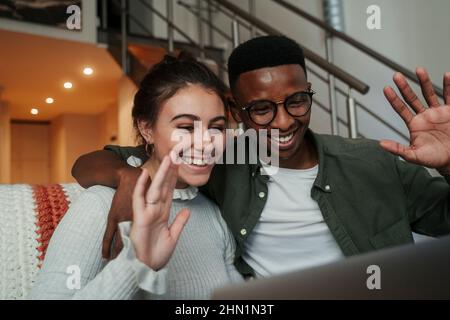 Afroamerikanischer Mann, der mit einer kaukasischen Freundin auf einem Videoanruf eines Laptops sitzt Stockfoto