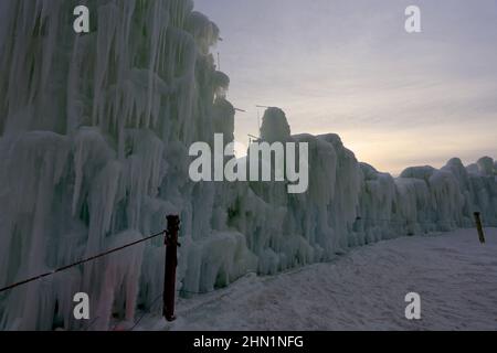 Eine Wand aus gefrorenen Eisblöcken und Eiszapfen, die am Genfer See, Wisconsin, USA, gegen den Himmel ragen Stockfoto