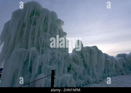 Eine Wand aus gefrorenen Eisblöcken und Eiszapfen, die am Genfer See, Wisconsin, USA, gegen den Himmel ragen Stockfoto