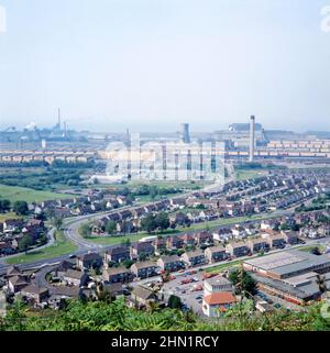 Ein Blick auf das Port Talbot Steelworks, ein integriertes Stahlproduktionswerk in Port Talbot, West Glamorgan, Wales, UK c. 1980. Die Hauptzufahrtsstraße zu dieser Zeit war die Cefn Gwrgan Road, die hier von unten links über eine Eisenbahnbrücke zum Werk führte. Diese Zufahrtsstraße wurde 2013 durch das Gebäude der Hafenstraße-Umgehungsstraße unterbrochen. Dieses Bild stammt aus einer Vintage-Farbtransparenz – einem Vintage-Foto aus dem Jahr 1970s/80s. Stockfoto