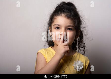 Porträt eines kleinen Mädchen geheim halten legte Finger in die Nähe der Lippen Zeichen zu schweigen Stockfoto