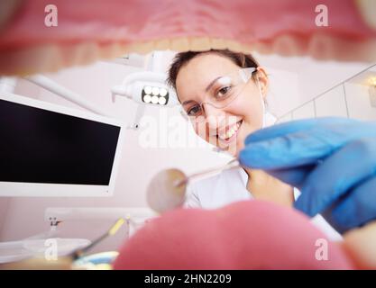 Die hübsche junge Zahnärztin untersucht die Zähne des Patienten. Blick von der Innenseite des Kiefers. Stockfoto