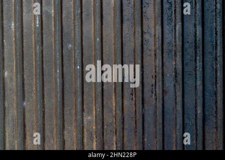 Dunkler vertikaler gerippter, verrosteter Grunge-Hintergrund. Alte Grillfläche aus Gusseisen Stockfoto