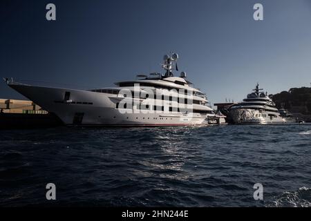 Zwei riesige Yacht im Hafen von Monaco bei Sonnenuntergang, glänzende Bord des Motorbootes, der verchromte Handlauf, Megayacht ist in der Marina vertäut, Sonnenreflexion Stockfoto