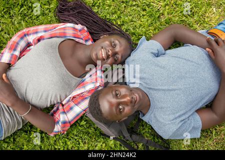 Afrikanische Jugendliche aus der High School entspannen sich auf dem Rasen in einem öffentlichen Park Stockfoto