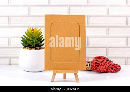 Bilderrahmen-Modell mit Blumentopf und Innendekorationen auf hellem Backstein Wand Hintergrund. Stockfoto