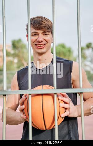 Porträt eines lächelnden jungen Athleten mit einem Basketball Stockfoto